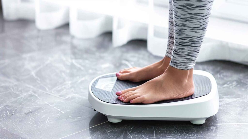 A woman weighing herself on a scale to check if her end of pregnancy weight loss is normal