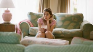 a woman holding a packet of birth control looking perplexed